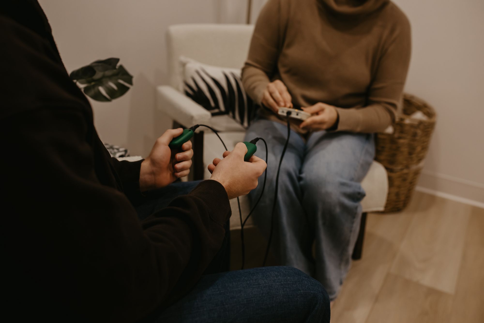 A client holding bilateral tappers while a therapist adjusts the device during a session